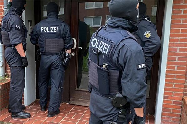 Beamte der Bundespolizei stehen vor einer Haustür in Leer. Hintergrund sind Ermittlungen wegen mutmaßlicher Schleuseraktivitäten.