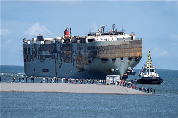 03.08.2023, Niederlande, Eemshaven: Schlepper ziehen den schwer beschädigten Aut...