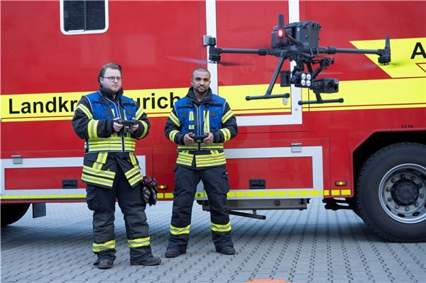 2 Männer steuern eine Drohne vor einem Feuerwehrfahrzeug