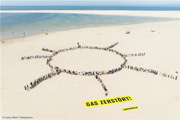 Ein Bohrturm, der sich in eine Sonne verwandelt - das soll das Motiv sein, das Greenpeace-Mitglieder und Insulaner auf dem Strand von Borkum formten.