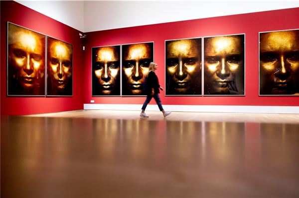 Eine junge Frau geht vor dem Werk ·Die Sonne um Mitternacht schauen III/196· der Künstlerin Katharina Sieverding in der Kunsthalle Emden entlang.