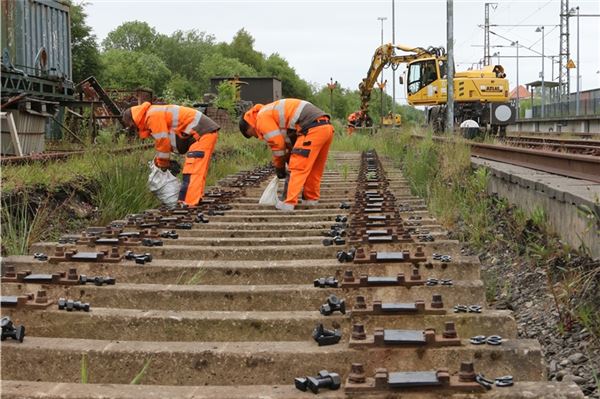 Mitarbeiter der Gleisbaufirma platzieren Kleineisen auf den Betonschwellen, mit denen das Gleis später fixiert wird.