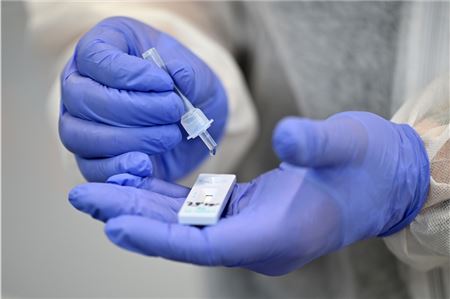 : Ein Helfer verarbeitet eine Probe für einen Corona-Schnelltest.