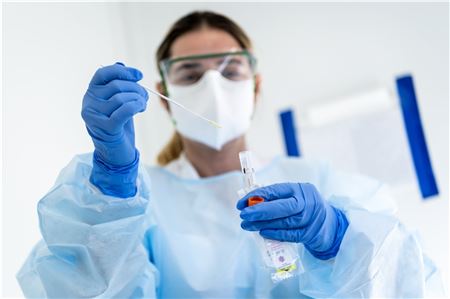  Eine Krankenschwester steckt im Krankenhaus n eine Probe mit einem Nasenabstrich eines Patienten in einen Behälter. 