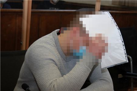 Der Angeklagte verdeckte zu Prozessbeginn sein Gesicht vor den Pressefotografen.