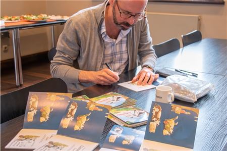 Der Autor und Illustrator Alexander Steffensmeier signiert plattdeutsche Exemplare seines Kinderbuches „Lieselotte luurt“.