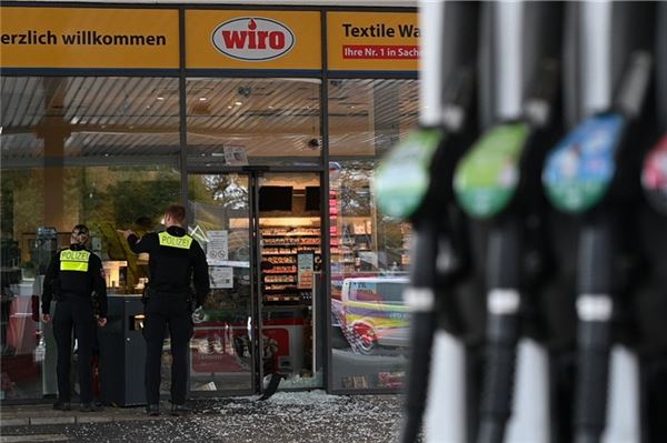 Einsatzkräfte der Polizei stehen nach der Sprengung eines Geldautomaten vor einer Tankstelle in der Innenstadt.