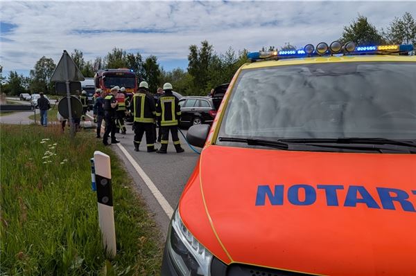 Ein Notarztwagen, im Hintergrund die Feuerwehr und die Verunfallten Fahrzeuge.
