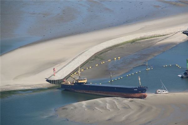 Ein Küstenmotorschiff liegt quer in der Hafeneinfahrt Wangerooge.