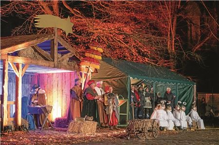 Ein stimmungsvolles Bild auf dem Norder Marktplatz: Maria und Josef mit dem Jesuskind, den Königen und den Engeln. Im Hintergrund sind die Chöre und Sprecher Andree Uphoff zu sehen.