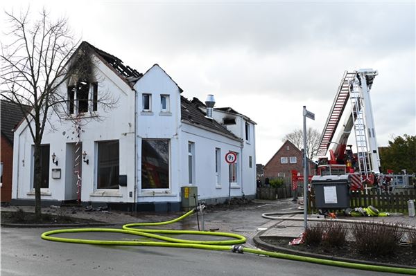 Eine Drehleiter der Feuerwehs steht vor einem ausgebrannten Haus. Bei dem Brand in Bunde waren rund 100 Rettungskräfte im Einsatz, um das Doppelhaus zu löschen und die Verletzten zu versorgen, wie ein Sprecher der Feuerwehr mitteilte. Foto: Lars Penning/dpa