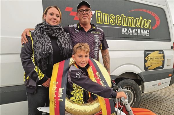 Eine Familie feiert gemeinsam. Julius Ruschmeier strahlt mit dem goldenen Siegerkranz. Der frisch gekürte Deutsche Meister der 50-ccm-Klasse wird zu jedem Rennen von seinen stolzen Eltern Maxine und Daniel Ruschmeier begleitet. Foto: Niklas Grönitz