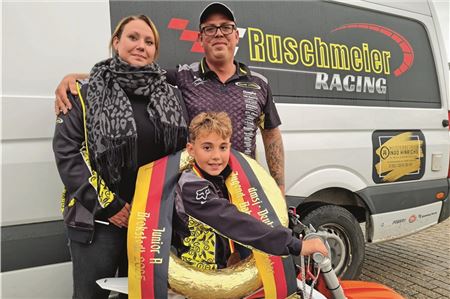 Eine Familie feiert gemeinsam. Julius Ruschmeier strahlt mit dem goldenen Siegerkranz. Der frisch gekürte Deutsche Meister der 50-ccm-Klasse wird zu jedem Rennen von seinen stolzen Eltern Maxine und Daniel Ruschmeier begleitet. Foto: Niklas Grönitz
