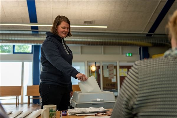 Großer Wahlzettel, großer Umschlag: Eine Frau geht in Norden zur Wahl.