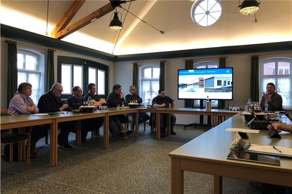 Jonas Heidbreker (rechts) stellt den Planungsentwurf für das Sportzentrum in Marienhafe vor, Ausschussmitglieder und die Chefs der Verwaltung hören interessiert zu. Foto: Hauke Eilers-Buchta