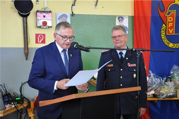Landrat Olaf Meinen (links) liest aus der Verabschiedungsurkunde vor, der scheidende Kreisbrandmeister Dieter Helmers lauscht ergriffen. Foto: privat