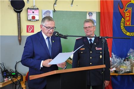 Landrat Olaf Meinen (links) liest aus der Verabschiedungsurkunde vor, der scheidende Kreisbrandmeister Dieter Helmers lauscht ergriffen. Foto: privat