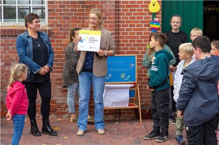 Leiterin Heidi Smidt präsentiert das Schild, das ihre Schule als Teilnehmer am Startchancen-Programm ausweist. Foto: Nicole Frischlich