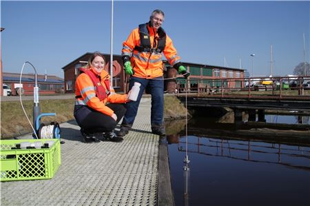 Martina Ritter und Carsten Didi nehmen eine Wasserprobe in Emden.